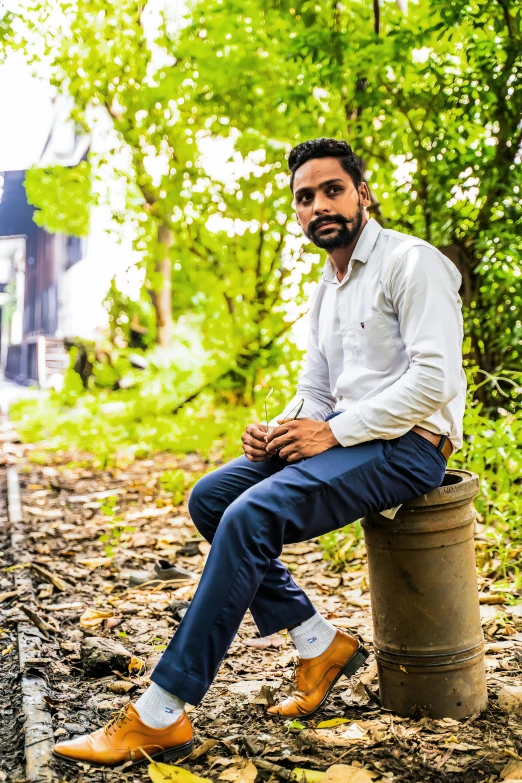 a man sits on a stump and stares into the distance