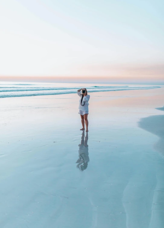 a woman is standing in the water looking at the beach