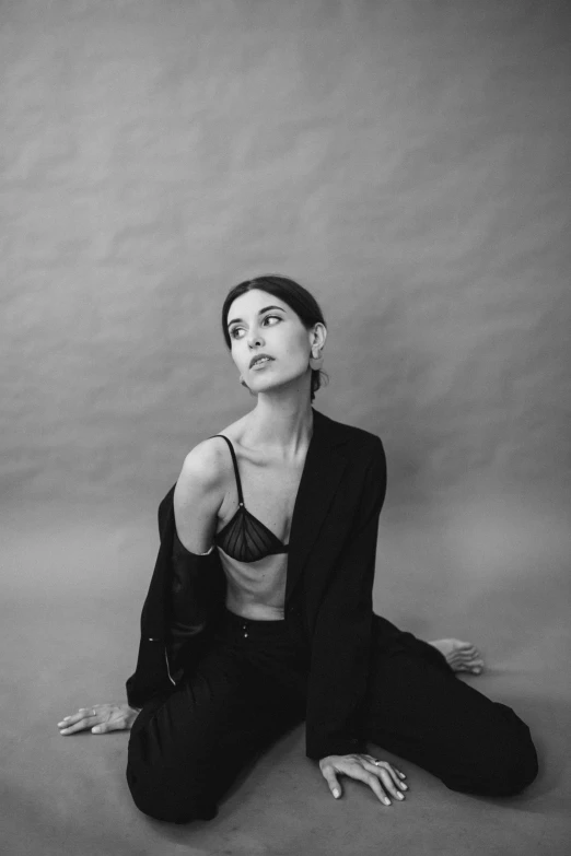 a woman is sitting on the ground in a black suit