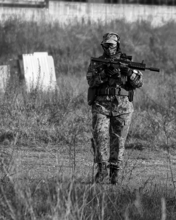 a man with a rifle is walking through the grass