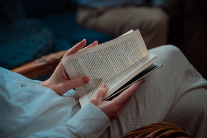 woman reading an open book on a white chair