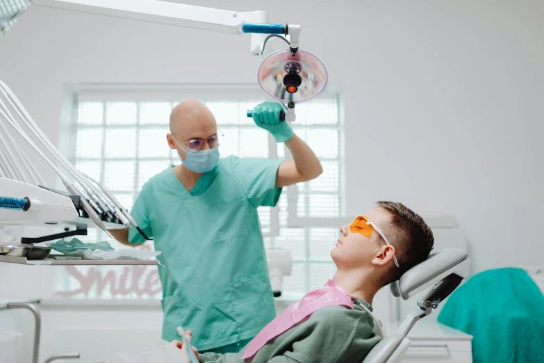 a woman laying in a dentist chair while a doctor looks on