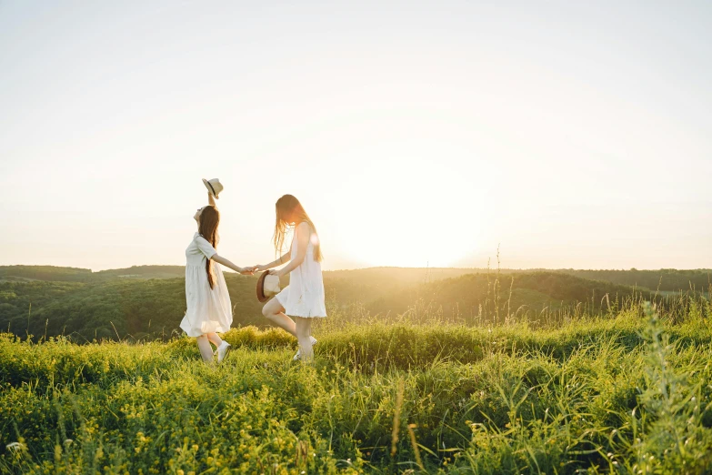 two women holding hands and walking in a field