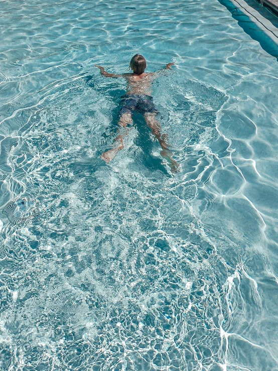 a girl is swimming in a pool wearing a swim suit