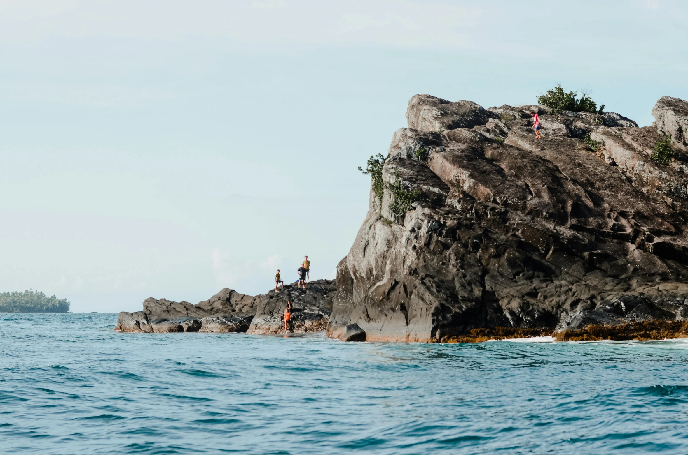 two people stand on the rocks near a body of water