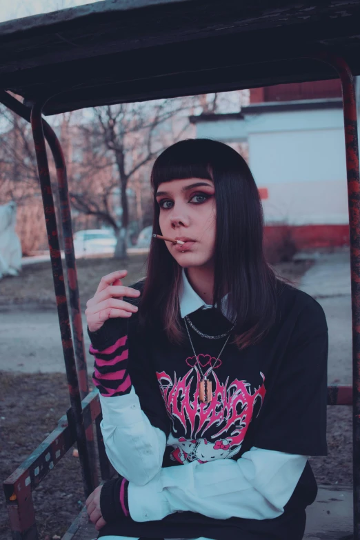 a girl sitting in a truck wearing a hoodie and smoking a cigarette