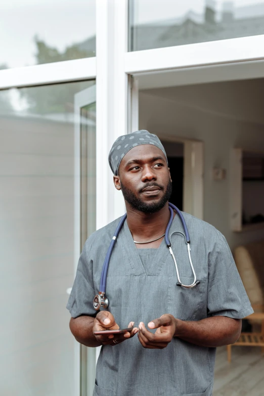 a male medical doctor in a grey uniform standing outside