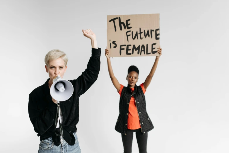 two women are holding a placard and a megaphone in the air