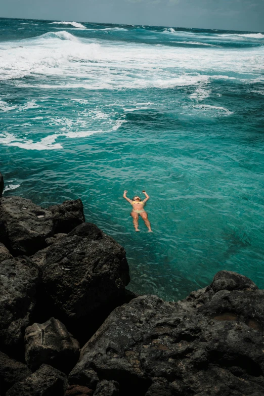 a man wading into a body of water near some rocks