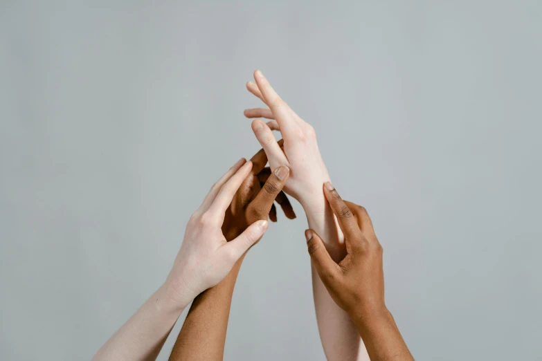 group of people reaching their hands up with hands raised