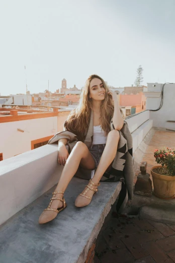 a beautiful woman sitting on top of a concrete ledge