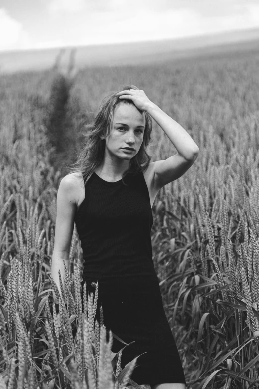 a woman in black is standing in a field of tall grass