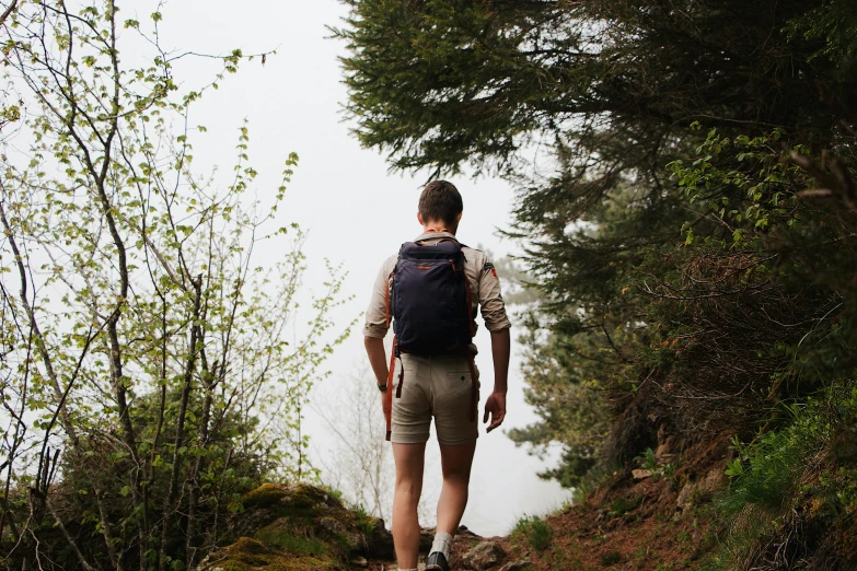 a young man walking up a steep incline in the woods