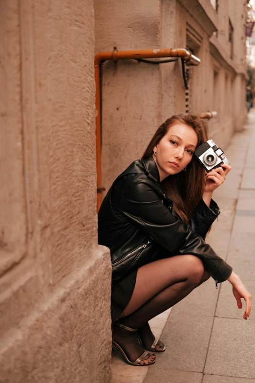 a girl posing with an old camera near the wall