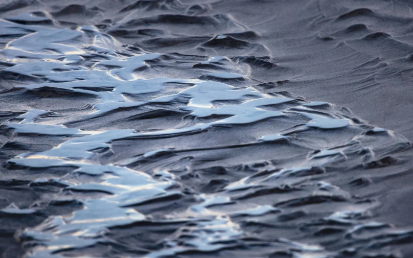 a wave covered sand is shown in black and white