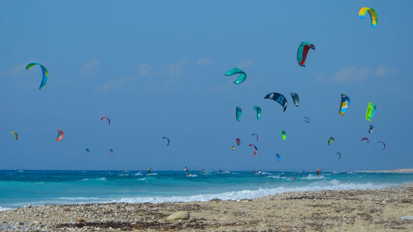 a group of people flying kites on the beach