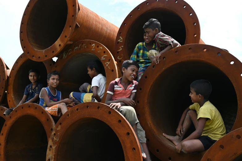 children are sitting in large pipes that look like soing they have turned into