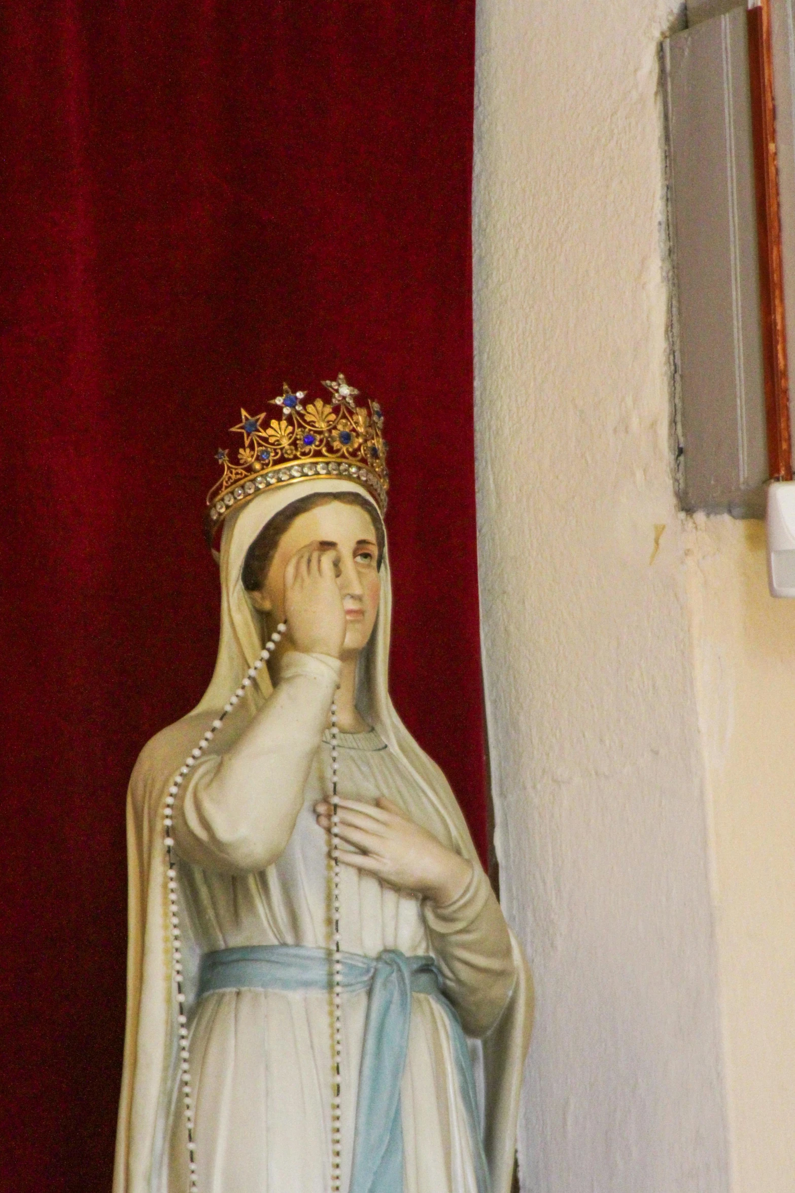 statue of queen mary with crown in front of red curtain