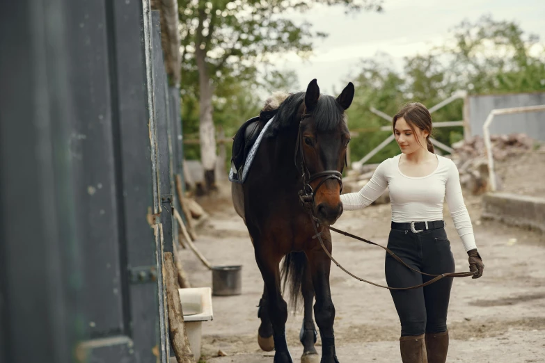 a woman holding the reigns of a horse next to its trainer