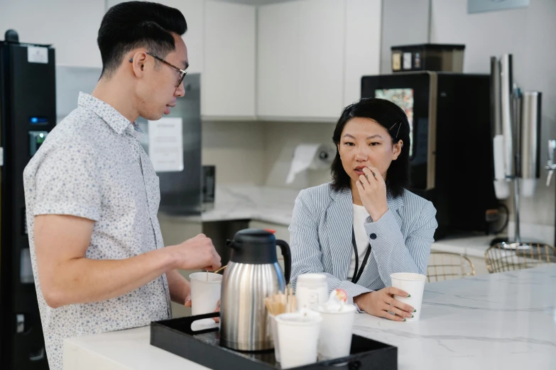 a man is talking to a woman while making soing at a kitchen counter