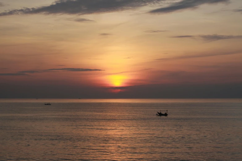 two boats are seen in the distance at sunset