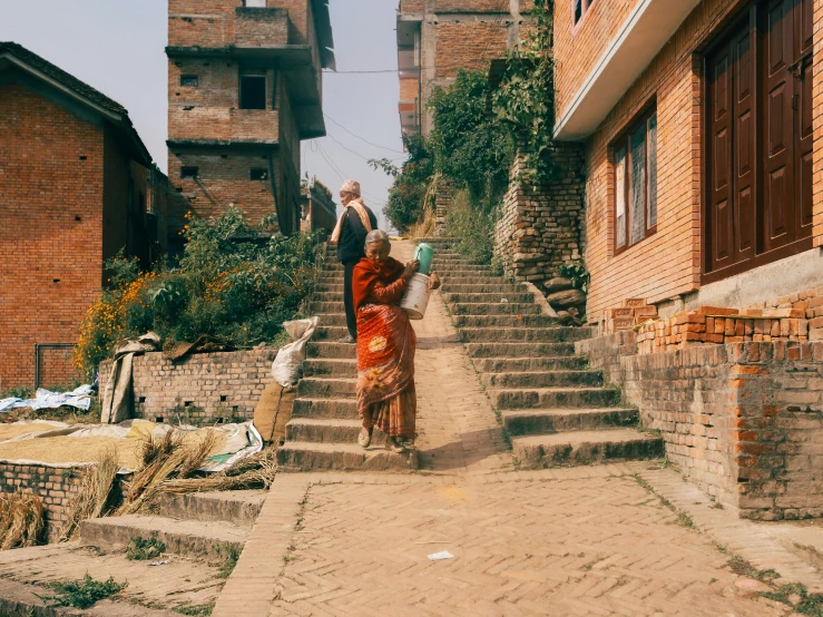 people walking down steps in an alley, with buildings in the background