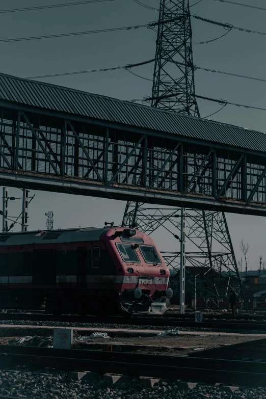 an orange train is on the tracks under the bridge