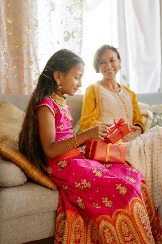 two beautiful young women sitting on top of a couch next to each other