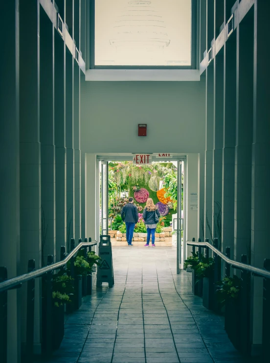 two people are walking through the hallway to a greenhouse