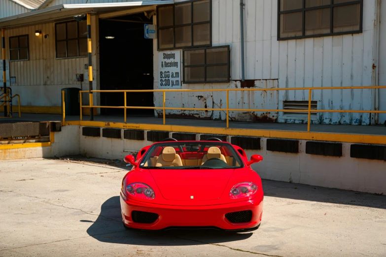 red ferrari parked in front of an old hangar