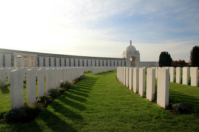 a long white cemetery with several graves sitting on the grass