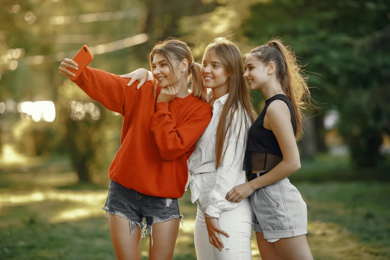 three young women taking a selfie in a park