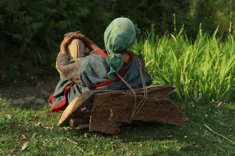 a girl sitting on a wooden log in the woods