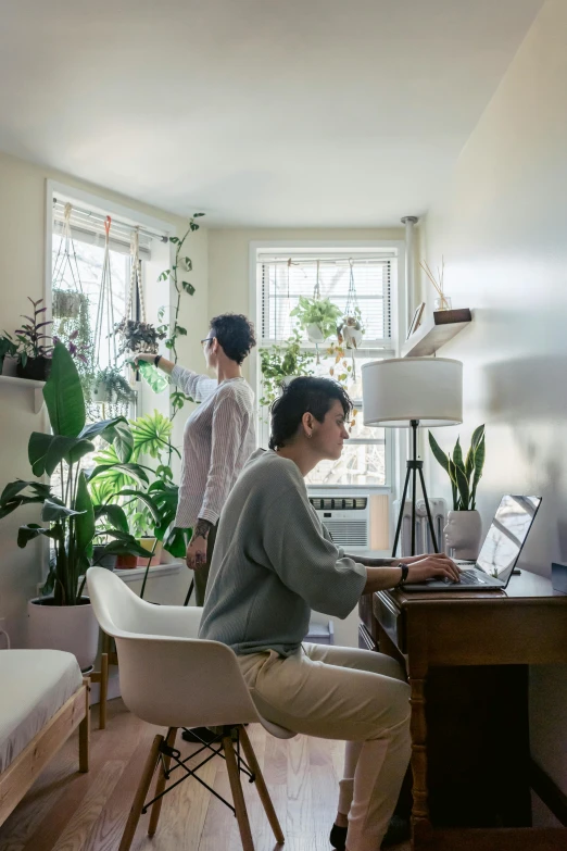 two women are using laptop computers in a small room