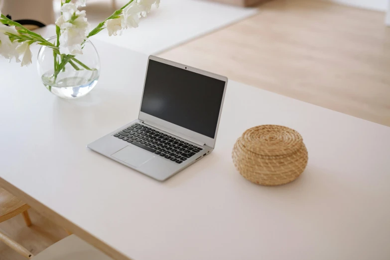 an empty vase is next to a laptop on a table