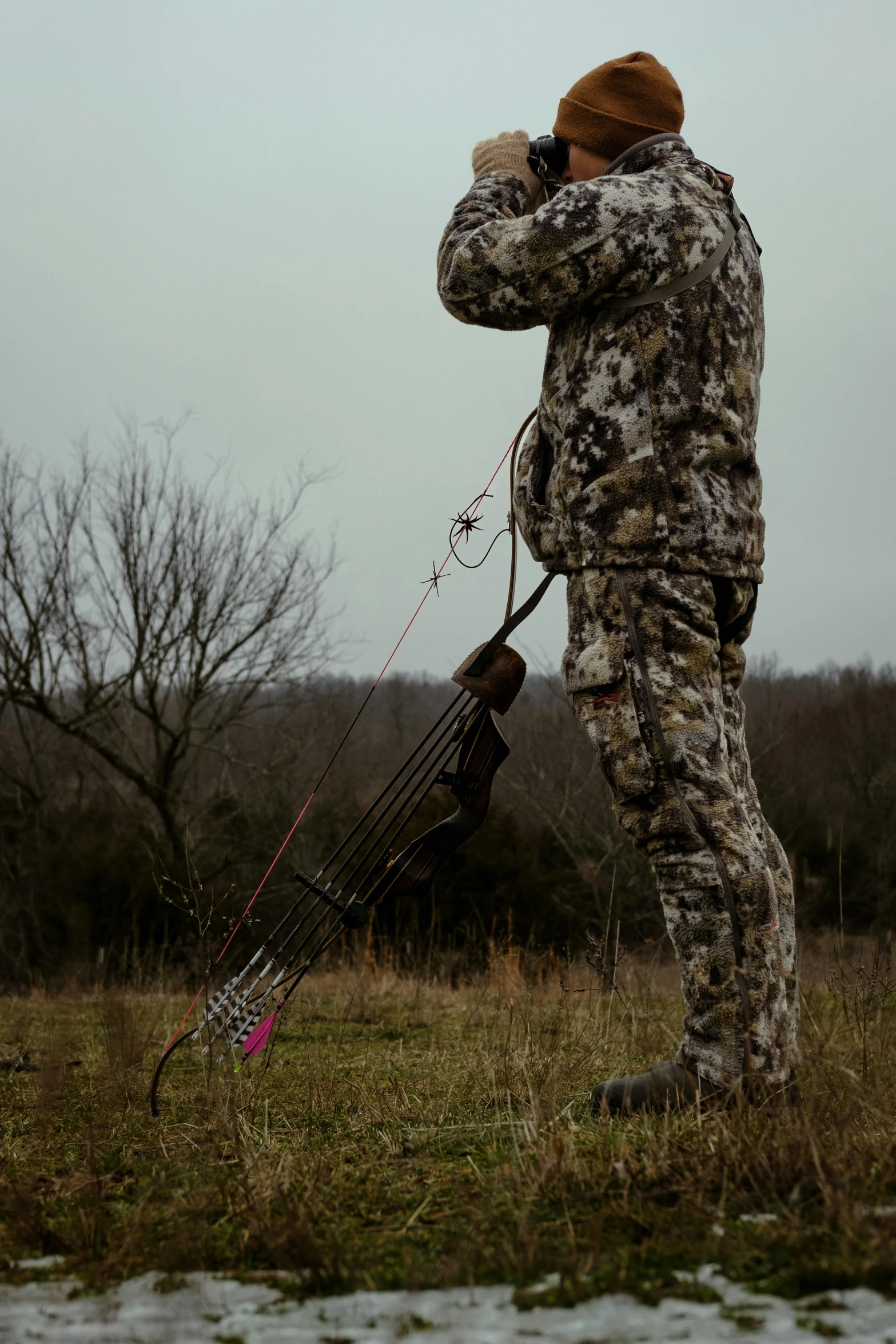 a man in camouflage with a bow and a gun