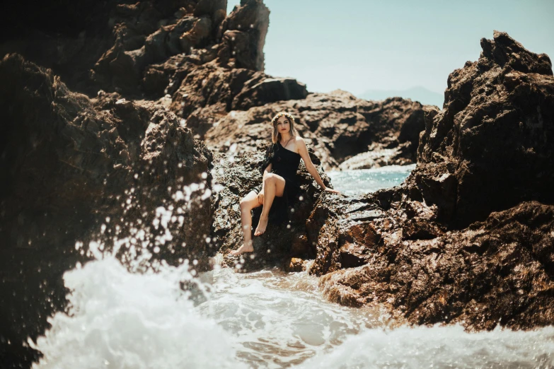 a woman is standing on the rocks in the ocean