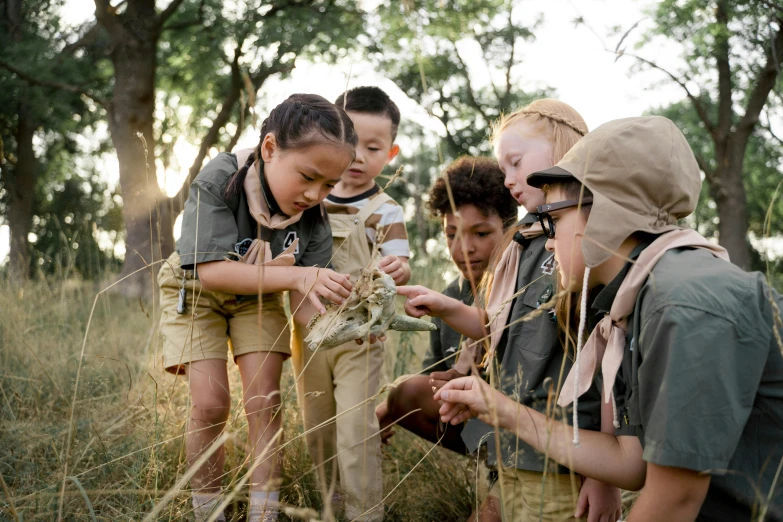 young children in safari clothes examine the animal on the grass