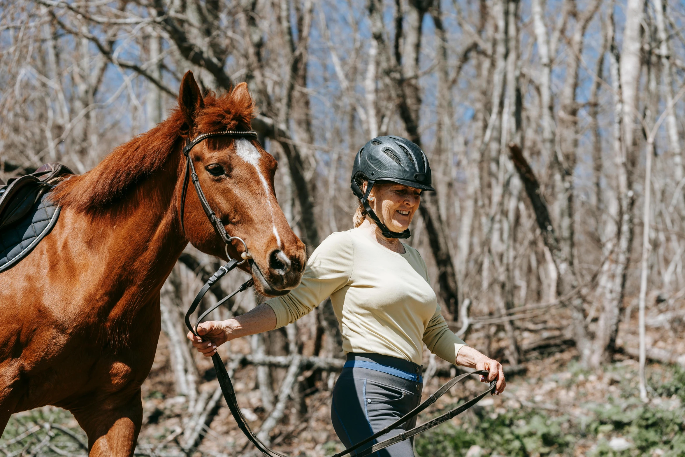 a woman riding a brown horse through a forest