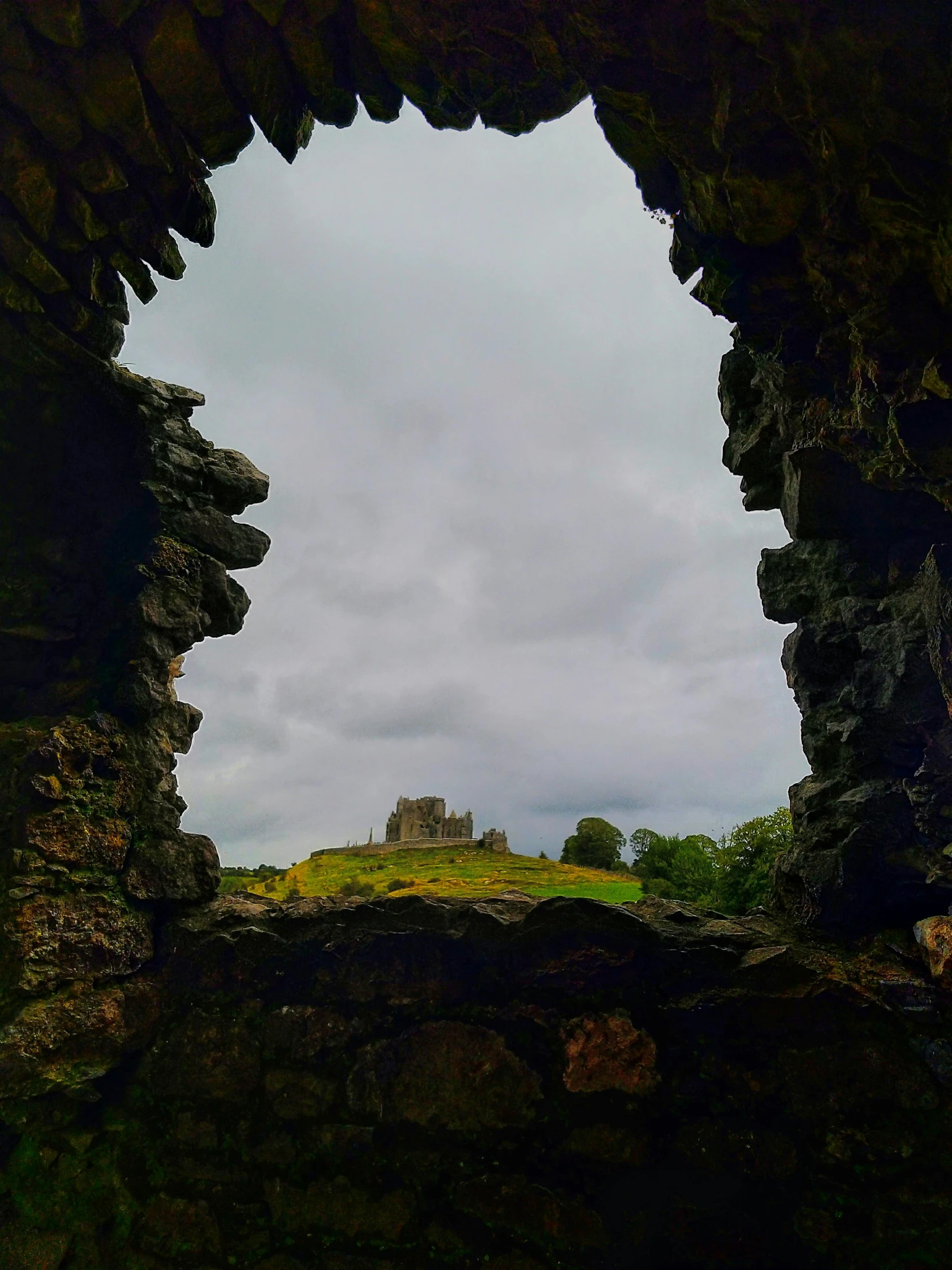 an archway that leads to the horizon over a small rock hill