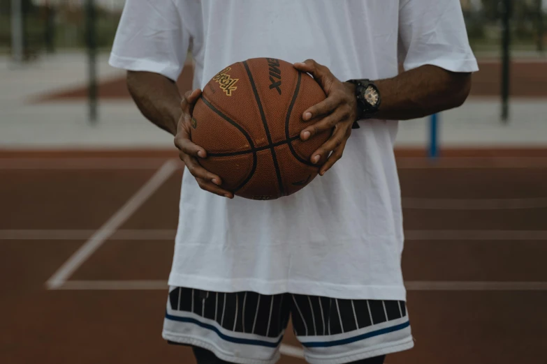 a basketball being held by someone's hands on a court