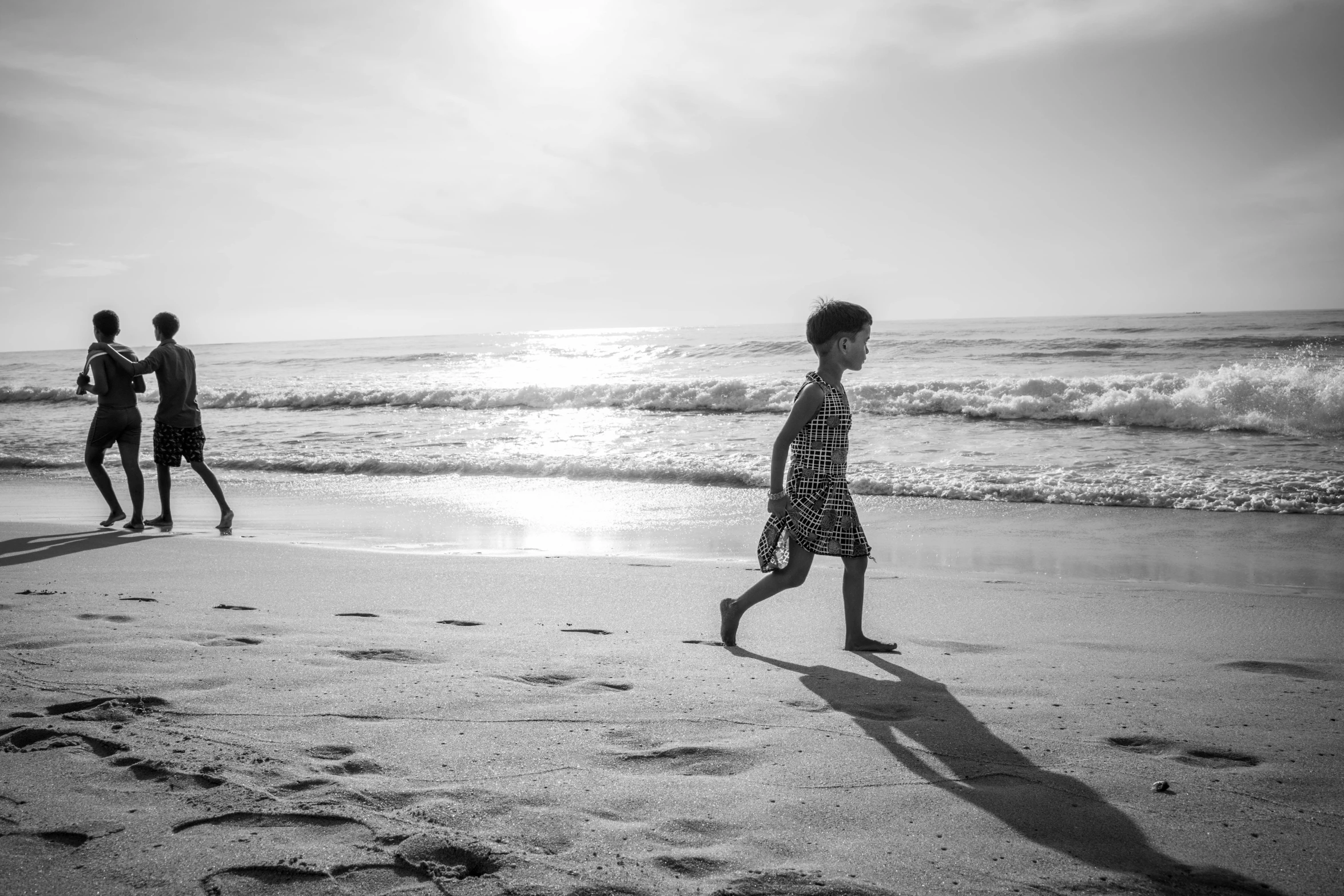 two children on the beach are walking near the water