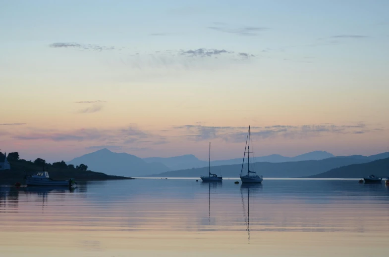 three boats sailing in the water during sunset