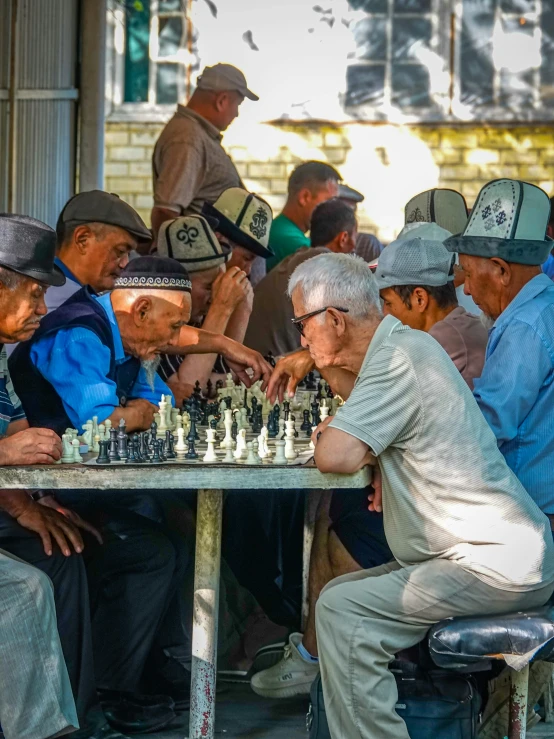 a number of people sitting at a table playing chess