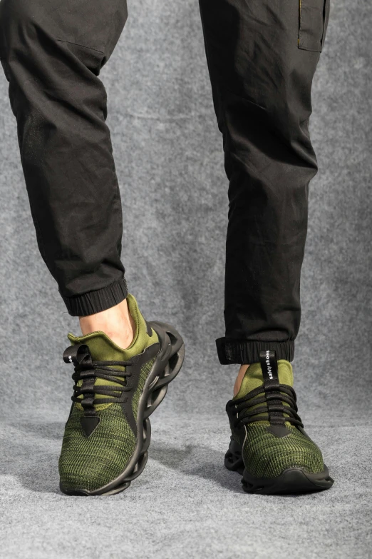 a close up of the feet of a man in black sweatpants, sneakers, and green pants