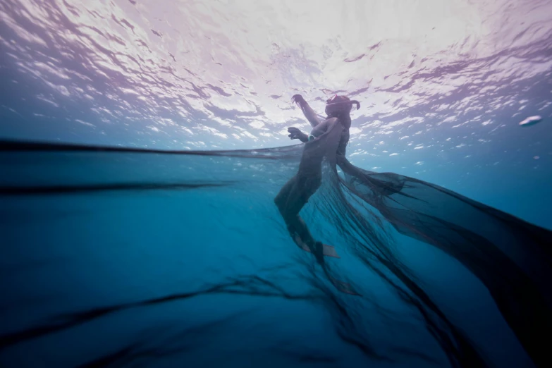 the person is s diving underwater in blue water