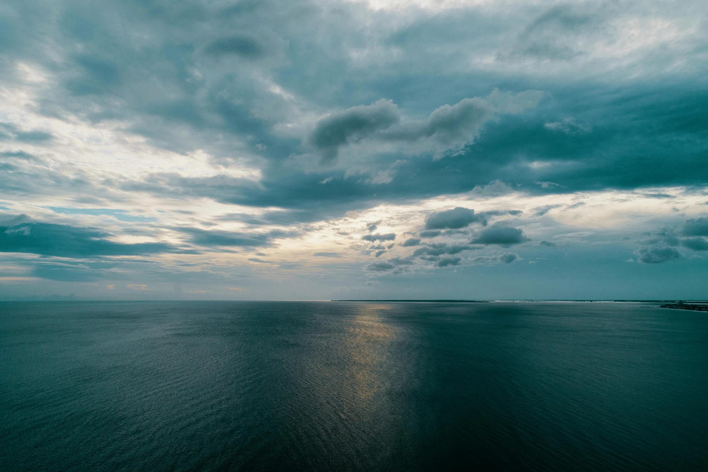 a long view from the water looking into a large body of water with many clouds in the background