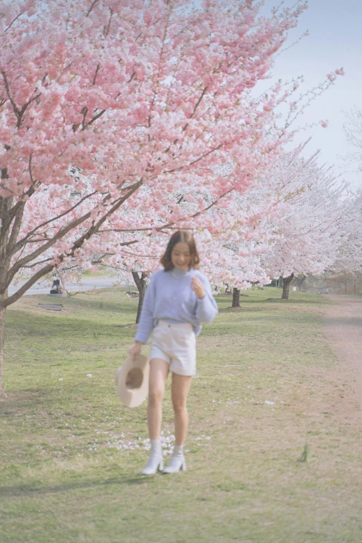 the young woman is walking beside the blooming tree