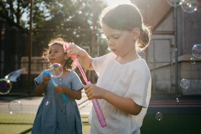 two little girls blowing bubbles in the backyard