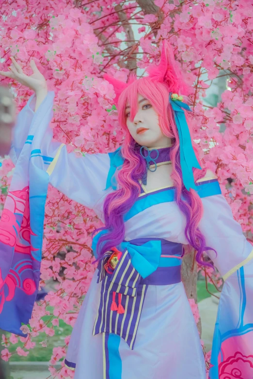 woman in costume posing next to tree of pink flowers